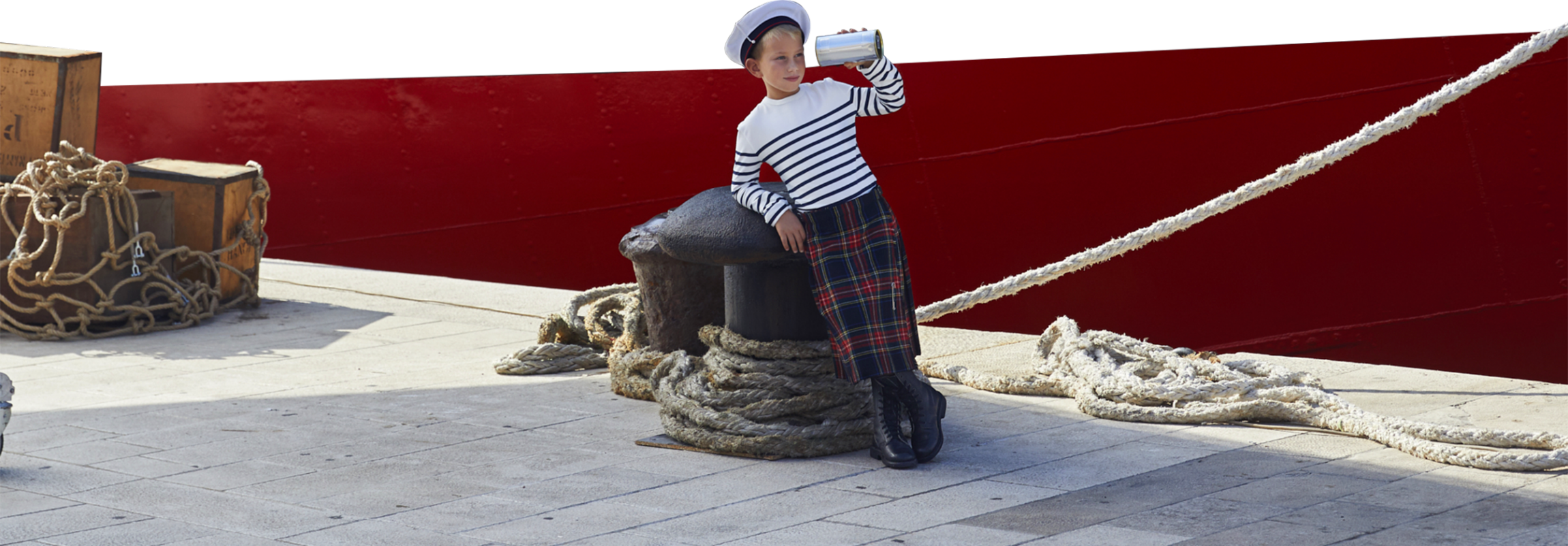 Visual of the new campaign with with a child in a kilt and striped shirt at quay holding a bottle of perfume like a long sight